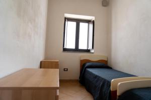 Zimmer mit 2 Betten, einem Tisch und einem Fenster in der Unterkunft Casa degli Ulivi in Pachino