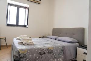 ein Schlafzimmer mit einem Bett mit einer Decke und einem Fenster in der Unterkunft Casa degli Ulivi in Pachino
