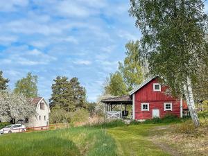 un granero rojo y una casa blanca en un campo en Holiday home LIDKÖPING X, en Tallbacken