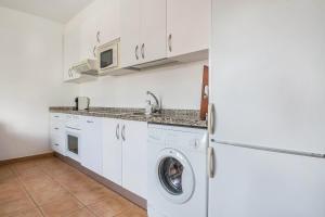cocina con armarios blancos, lavadora y secadora en Casa Yerida en Cotillo