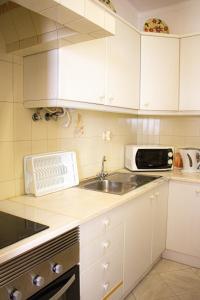 a kitchen with white cabinets and a sink and a microwave at Casa Maria in Albufeira