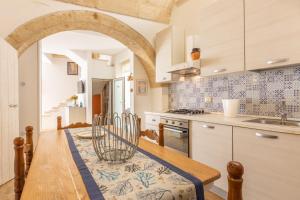 cocina con mesa de madera con sillas y fregadero en Dimora il Castello, en Racale