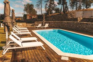 a swimming pool with lounge chairs next to a stone wall at Moinho d'Antoninha in Leomil