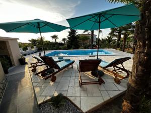 a group of chairs and umbrellas next to a pool at Holiday House Serenity in Malinska