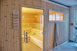 a sauna with wooden walls and a glass door at Struck Landhotel & SPA in Attendorn