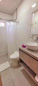 a white bathroom with a sink and a toilet at Colorful Garden House in Providencia