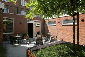 een patio met stoelen en tafels en een gebouw bij Hotel Dekkers in Ossendrecht