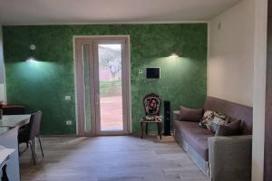 un soggiorno con pareti verdi e divano di appartamento Margherita a Crespina