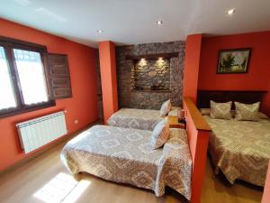 Dos camas en una habitación con paredes naranjas. en Hotel Rural Pajarapinta, en Molinaseca