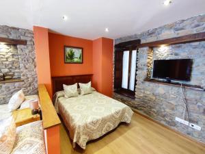 a bedroom with a bed and a stone wall at Hotel Rural Pajarapinta in Molinaseca