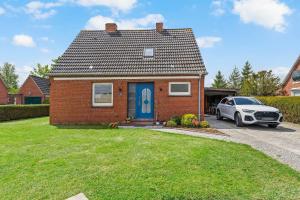 a brick house with a blue door and a car at Huus Frieda in Krummhörn