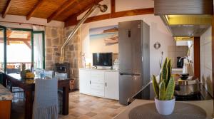 uma cozinha com um frigorífico de aço inoxidável e uma mesa em Mayia Sunset sea front house Gouves Heraklion em Gouves