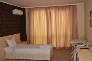 a bedroom with a bed and a desk and a window at La Piazza Primorsko Rooms & Apartments in Primorsko