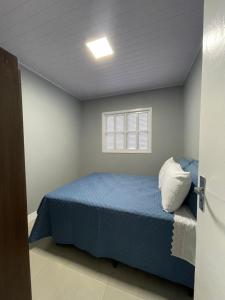 a bedroom with a blue bed and a window at Edícula Cambará in Cambará