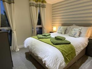 a bedroom with a bed with green towels on it at Elora's Dream in Wisbech