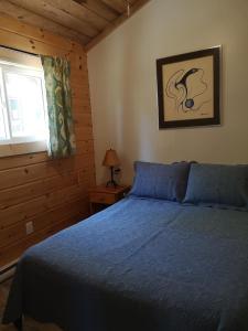 a bedroom with a blue bed and a window at The Pines Cottage Resort in Oxtongue Lake