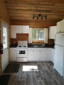 The Pines Cottage Resort في Oxtongue Lake: مطبخ بأدوات بيضاء وسقف خشبي
