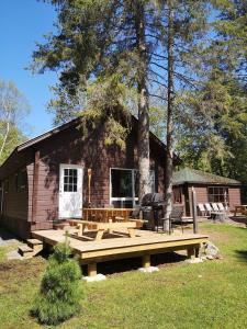 een blokhut met een houten terras ervoor bij The Pines Cottage Resort in Oxtongue Lake
