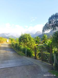 a road with a fence and mountains in the background at Vale da Paz in Guapimirim