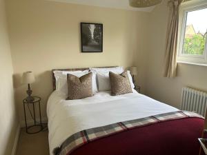 Un dormitorio con una cama blanca con almohadas y una ventana en Scalby Grove Cottage, en Scarborough