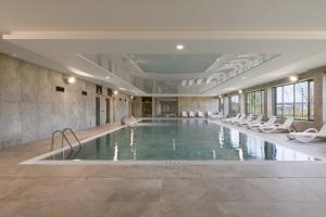 a large swimming pool with white chairs in a building at Apartament Marina Loft & Spa Sagaris Dziwnów in Dziwnów