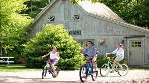 three children riding bikes in front of a barn at Hidden Pond Resort in Kennebunkport