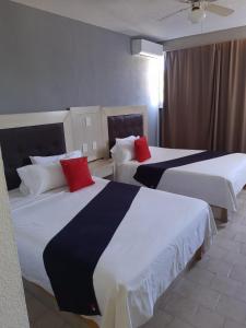 Dos camas en una habitación de hotel con almohadas rojas. en HOTEL SiCILIA iTALIA, en Aguascalientes