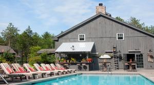 a barn with chairs next to a swimming pool at Hidden Pond Resort in Kennebunkport