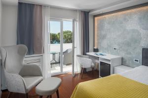 ein Schlafzimmer mit Bett, Schreibtisch und Fenster in der Unterkunft Hotel Tomi in Portorož