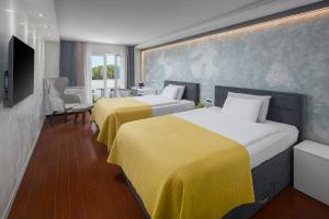 ein Hotelzimmer mit zwei Betten und einem Fernseher in der Unterkunft Hotel Tomi in Portorož