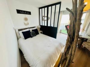 - une chambre avec un grand lit blanc et un arbre dans l'établissement L’Atelier des rêves à 200 m de la plage, à Fort-Mahon-Plage
