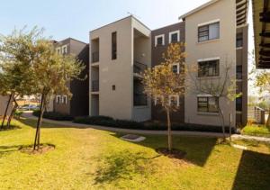 ヨハネスブルグにあるThe Steynview Apartment - Fourways Sandtonの庭に木が2本あるアパートメントビル