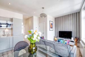 ein Wohnzimmer mit einer Vase aus Blumen auf einem Glastisch in der Unterkunft Elegant 1 bed apartment- Hampstead Village in London