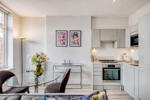 a white kitchen with a glass table in a room at Elegant 1 bed apartment- Hampstead Village in London