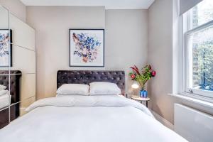 a white bedroom with a large bed and a window at Elegant 1 bed apartment- Hampstead Village in London