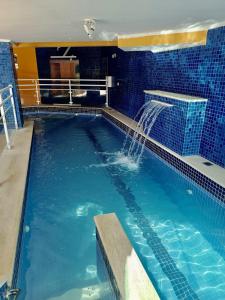 a swimming pool with a water fountain in a building at Hotel Canto da Riviera in Riviera de São Lourenço