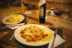 Garda Hotel في لارانجيراس دو سول: طاولة مع طبقين من المعكرونة وزجاجة من النبيذ