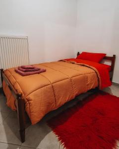 a bed with an orange comforter and a red rug at Mountain View in Konitsa