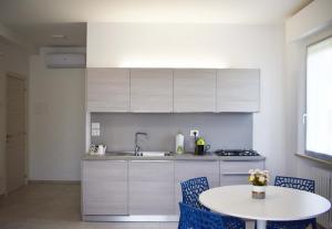 a kitchen with white cabinets and a table with chairs at Marcelli Mare Camere Nel Conero in Numana