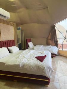 1 Schlafzimmer mit 2 Betten und weißer Bettwäsche in der Unterkunft Bubbles Oasis Camp Wadi Rum in Wadi Rum