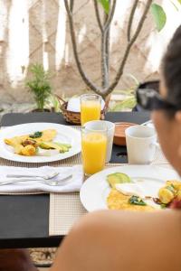 a table with plates of food and glasses of orange juice at Casa Dos Lirios Hotel Boutique in Mérida