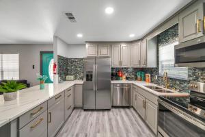a kitchen with white cabinets and a stainless steel refrigerator at Bungalow 1mile from Beach TVs Games Backyard in Navarre