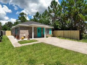 a small house with a blue door in a yard at Bungalow 1mile from Beach TVs Games Backyard in Navarre