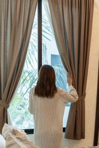Una donna con un maglione che guarda fuori dalla finestra di Casa Dos Lirios Hotel Boutique a Mérida