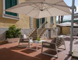 a patio with two chairs and a table and an umbrella at Euvodia Luxury Rooms in Matera