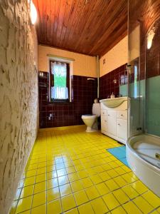 a bathroom with a yellow tile floor and a tub and sink at Austeria Przyjezierze in Pojezierze +58 photos
