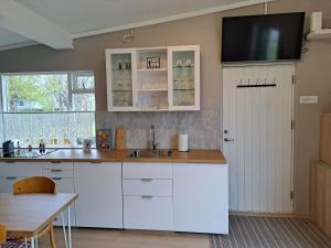 a kitchen with white cabinets and a tv on the wall at Apartment in the center in Húsavík