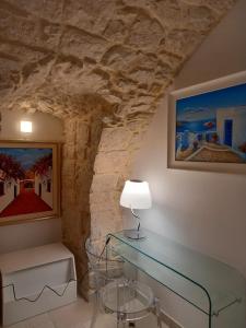 a glass table in a room with a stone wall at Suite Duomo Trani 6 in Trani