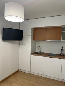 a kitchen with white cabinets and a flat screen tv at Orbi Palace Bakuriani Apartment in Bakuriani