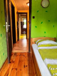 a green bedroom with a bed and a wooden floor at Austeria Przyjezierze in Pojezierze